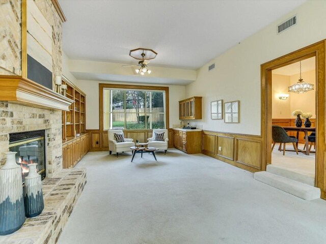 sitting room featuring a brick fireplace, light carpet, and an inviting chandelier