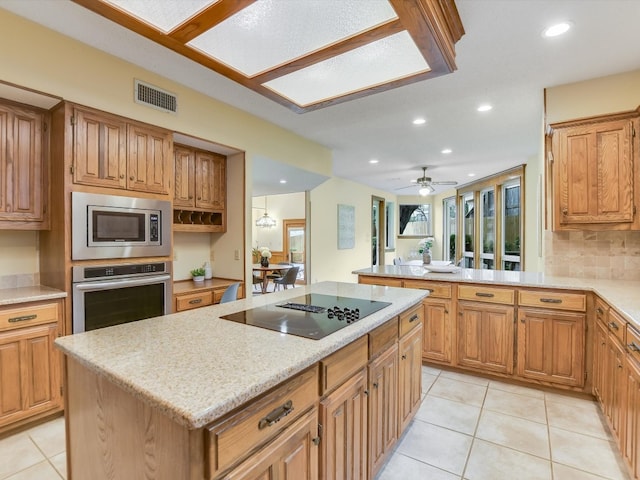 kitchen with light tile patterned flooring, stainless steel appliances, a healthy amount of sunlight, and a kitchen island