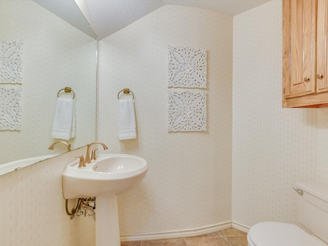 bathroom featuring lofted ceiling, toilet, tile patterned flooring, and a textured ceiling