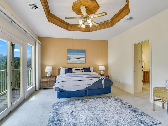 bedroom featuring ornamental molding, access to outside, a tray ceiling, light carpet, and ensuite bath