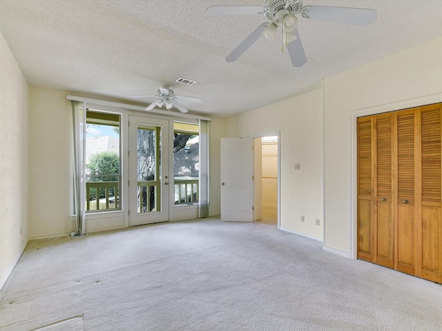 unfurnished bedroom with ceiling fan, access to outside, light colored carpet, and a textured ceiling