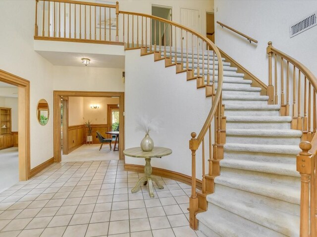 stairway with a high ceiling and tile patterned flooring