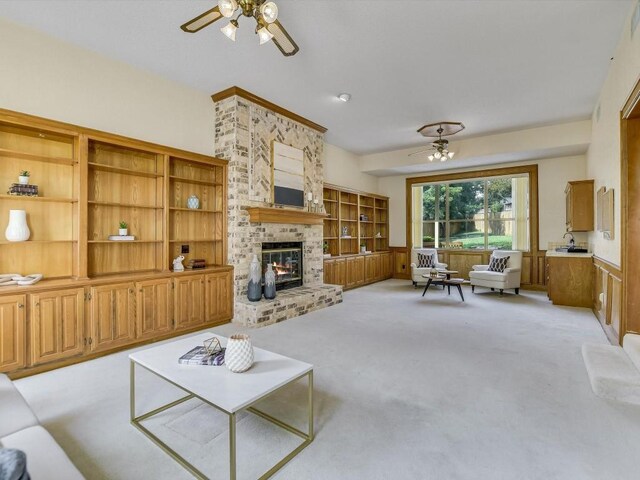 living room featuring ceiling fan, a fireplace, and light colored carpet