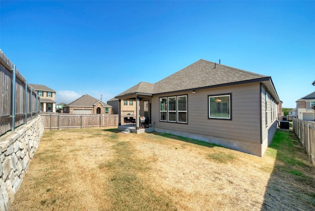 back of property featuring a lawn, a patio area, a shingled roof, and a fenced backyard