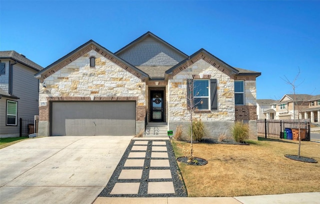 view of front of property featuring a front yard, a garage, stone siding, concrete driveway, and fence