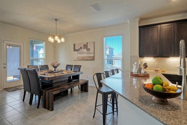 dining room with an inviting chandelier, light tile patterned floors, visible vents, and ornamental molding