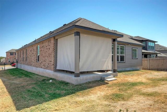 view of property exterior with fence, a yard, and brick siding