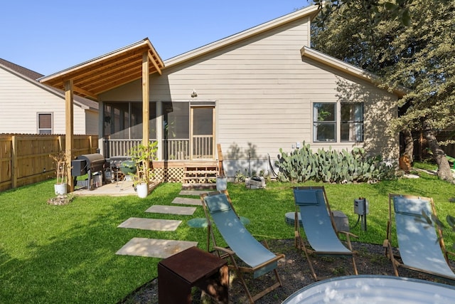 back of property featuring a lawn, a sunroom, and a patio