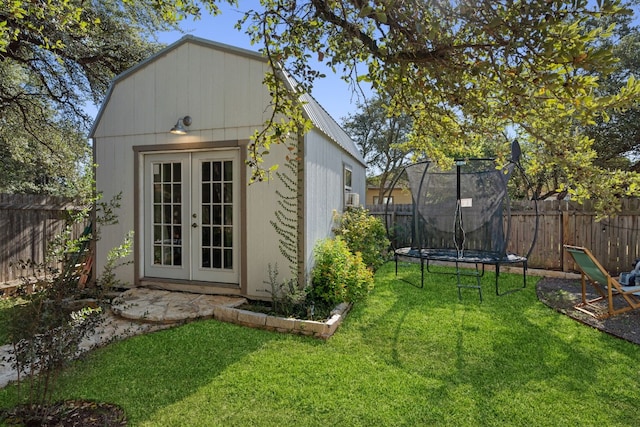 view of outdoor structure featuring french doors, a trampoline, and a lawn