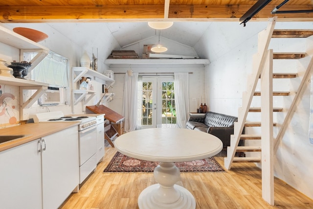 kitchen featuring white gas range, french doors, light hardwood / wood-style flooring, lofted ceiling with beams, and white cabinets