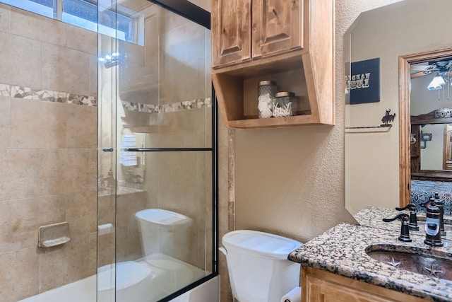 full bathroom featuring vanity, combined bath / shower with glass door, toilet, and ceiling fan