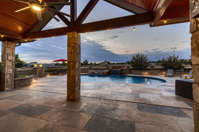 pool at dusk with a patio, pool water feature, a gazebo, and ceiling fan