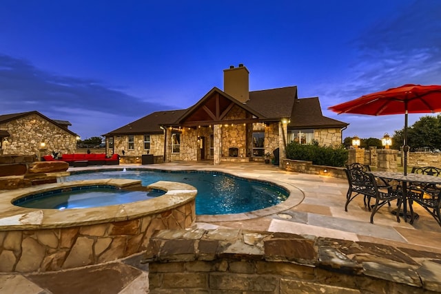 pool at dusk featuring a patio and an in ground hot tub