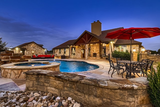 pool at dusk with an in ground hot tub and a patio