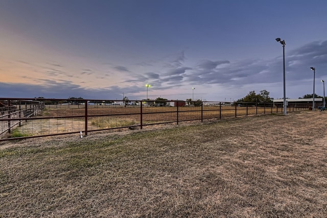 yard at dusk featuring a rural view