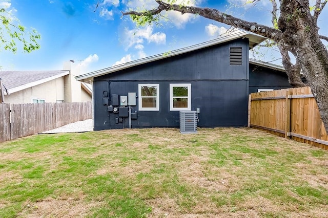 rear view of house with a lawn and central AC unit