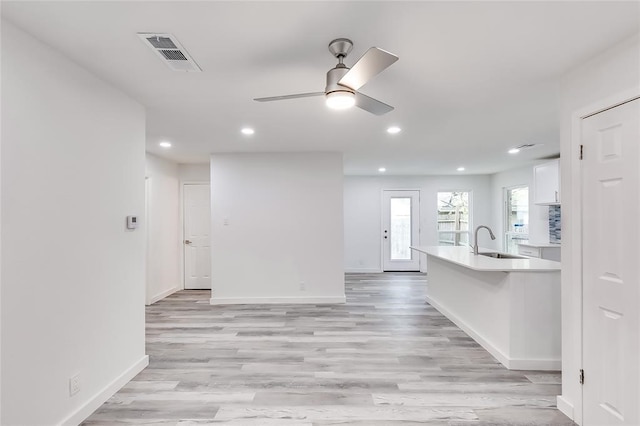 kitchen featuring white cabinets, sink, light wood-type flooring, and ceiling fan