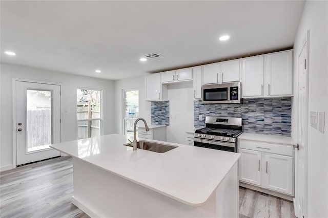 kitchen featuring light hardwood / wood-style flooring, an island with sink, stainless steel appliances, sink, and white cabinetry