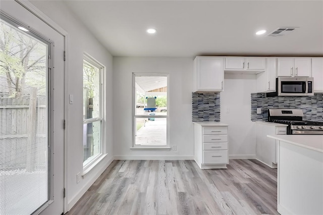 kitchen with stainless steel appliances, decorative backsplash, light hardwood / wood-style flooring, and white cabinets