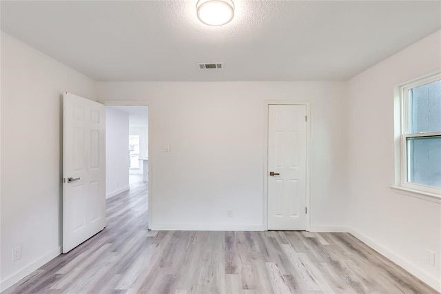 empty room featuring a textured ceiling and light hardwood / wood-style floors