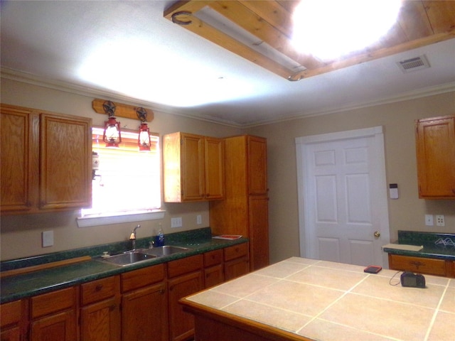 kitchen with crown molding, sink, tile counters, and a kitchen island