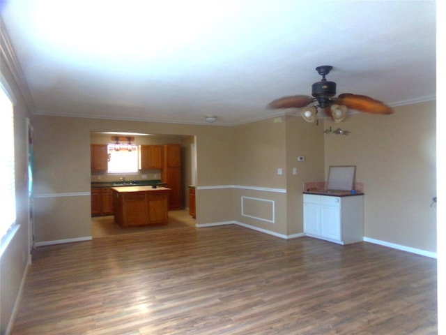 unfurnished living room featuring crown molding, dark hardwood / wood-style floors, sink, and ceiling fan