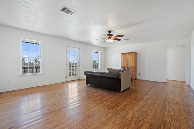 living room featuring a textured ceiling, light wood-type flooring, and ceiling fan