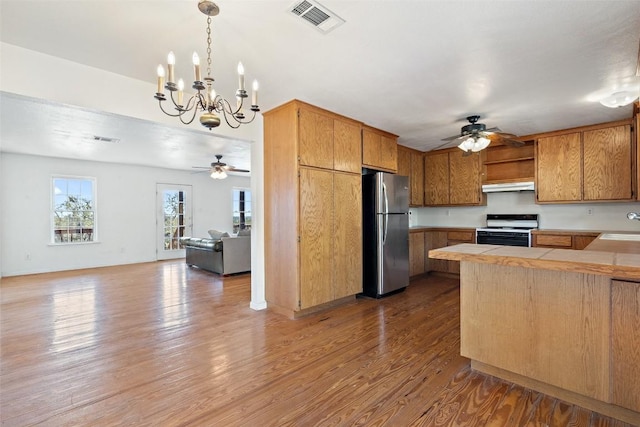 1401 Pursley Rd, Dripping Springs, TX 78620 - kitchen with gas range, under cabinet range hood, freestanding refrigerator, and ceiling fan with notable chandelier