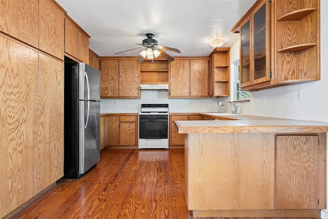 kitchen featuring sink, white range, kitchen peninsula, stainless steel fridge, and dark wood-type flooring