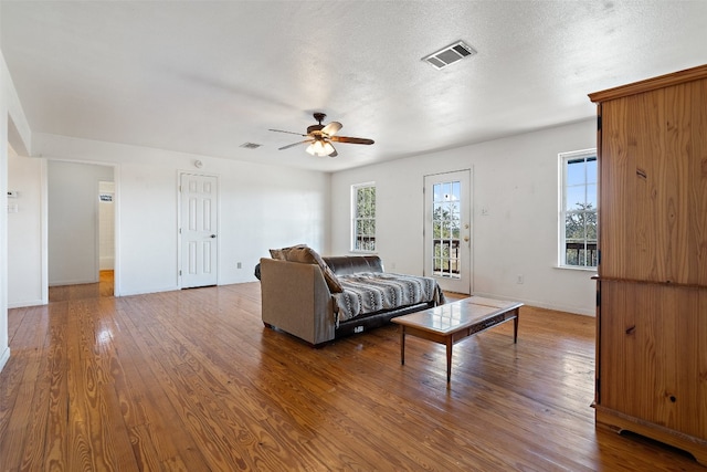 living room featuring hardwood / wood-style floors, a textured ceiling, and ceiling fan