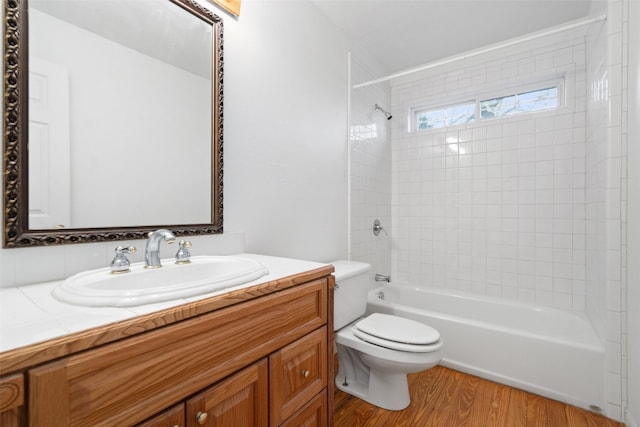 full bathroom with vanity, toilet, wood-type flooring, and tiled shower / bath