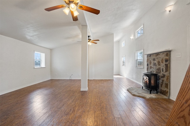 unfurnished living room with a wood stove, high vaulted ceiling, dark wood-type flooring, and ceiling fan