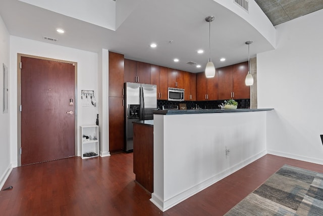 kitchen with pendant lighting, dark wood-type flooring, stainless steel appliances, and kitchen peninsula