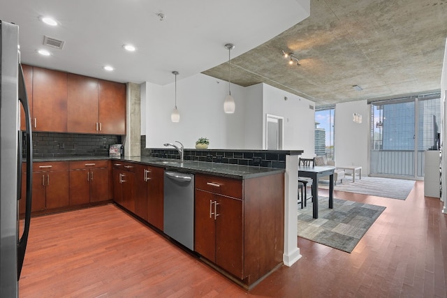 kitchen featuring hanging light fixtures, appliances with stainless steel finishes, hardwood / wood-style flooring, and kitchen peninsula