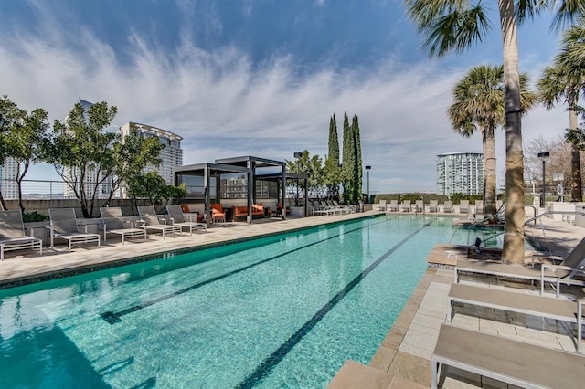 pool featuring a city view, a patio, and fence