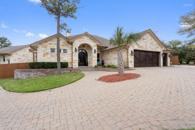 111 Kolekole Ln, Bastrop, TX 78602 - view of front of home with stone siding, a garage, and curved driveway