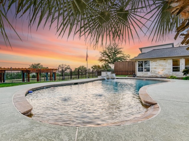 pool at dusk with a patio area and pool water feature