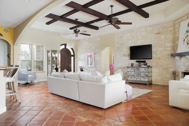 tiled living room with a towering ceiling, beam ceiling, coffered ceiling, and ceiling fan