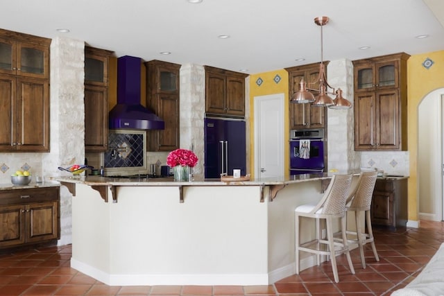 kitchen featuring high quality fridge, a breakfast bar, stainless steel oven, and custom range hood