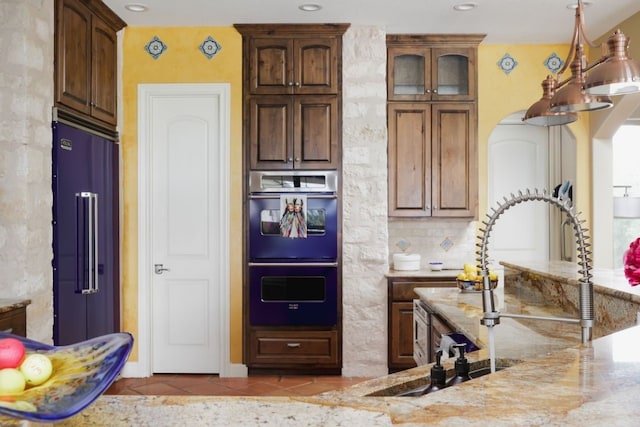 111 Kolekole Ln, Bastrop, TX 78602 - kitchen with high end refrigerator, double wall oven, light stone countertops, tile patterned floors, and decorative backsplash