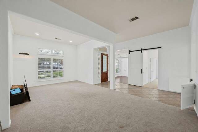 carpeted empty room featuring a barn door