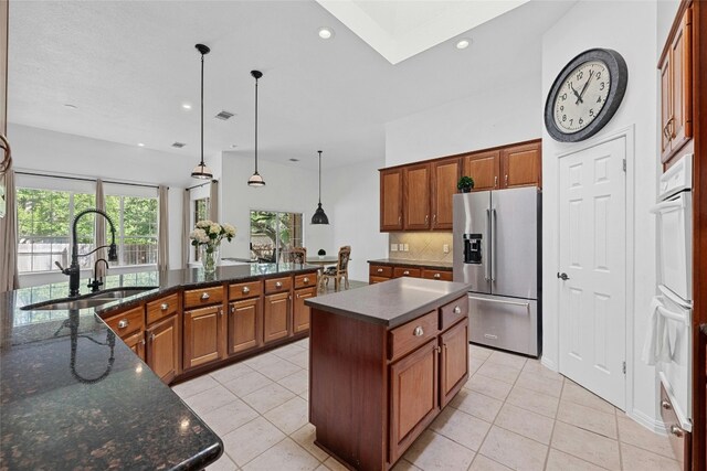 kitchen with sink, pendant lighting, a center island with sink, and stainless steel refrigerator with ice dispenser