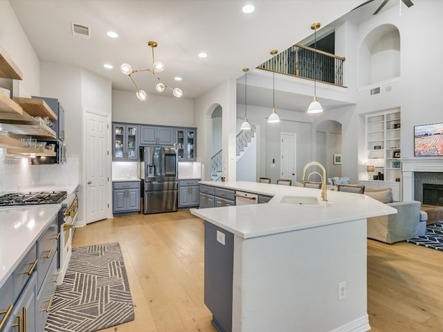 kitchen featuring sink, decorative light fixtures, gray cabinets, appliances with stainless steel finishes, and light hardwood / wood-style floors