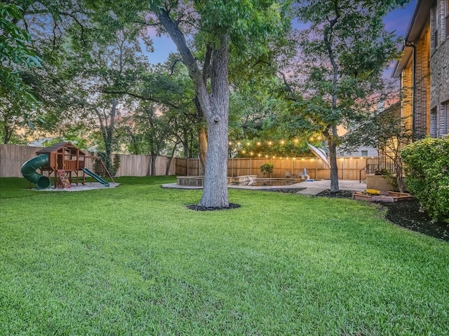 yard at dusk featuring a patio area and a playground