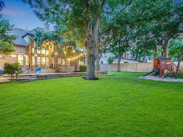 yard at dusk featuring a playground