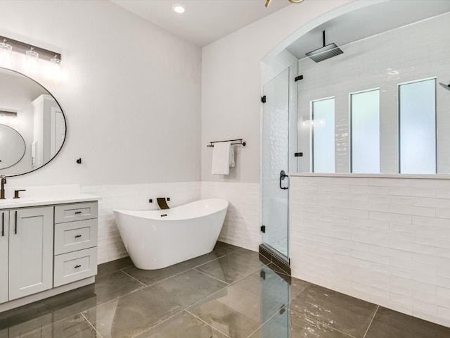 bathroom with vanity, independent shower and bath, tile walls, and tile patterned flooring