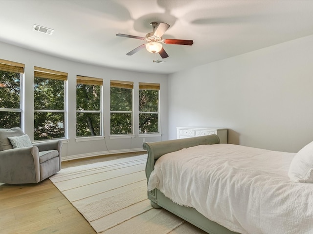 bedroom with ceiling fan, multiple windows, and light wood-type flooring