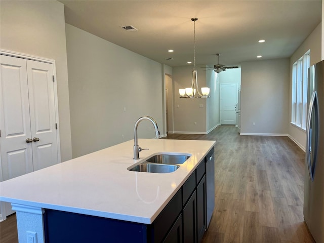 kitchen featuring stainless steel appliances, sink, pendant lighting, hardwood / wood-style flooring, and an island with sink