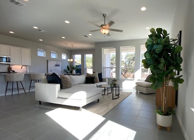 living room featuring ceiling fan with notable chandelier, light tile patterned floors, and sink