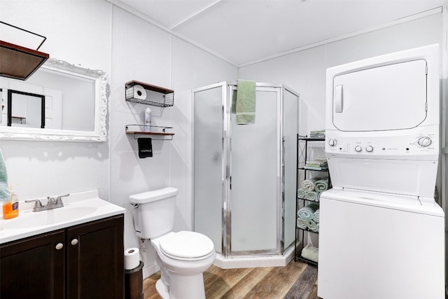 bathroom with a shower with door, toilet, stacked washing maching and dryer, wood-type flooring, and vanity